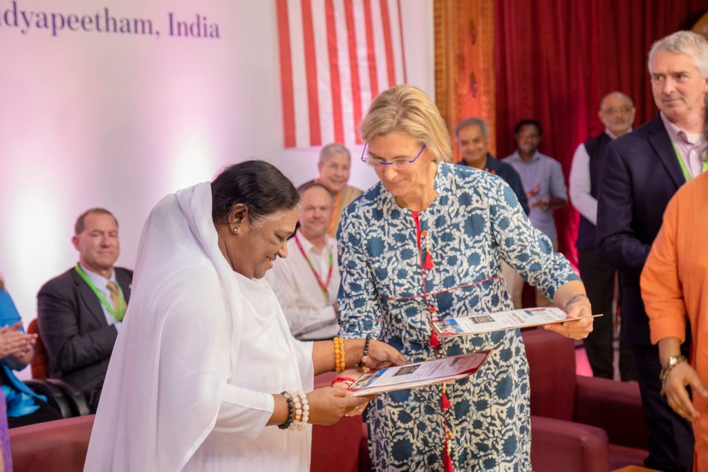 Amma and Dr. Liesl Folks looking at the letters of intent as the rest of the functionaries watch and clap.