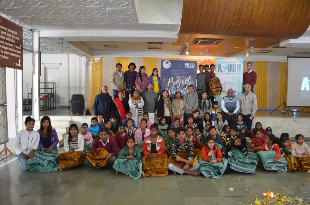 Children who received blankets sit in front of ashram volunteers