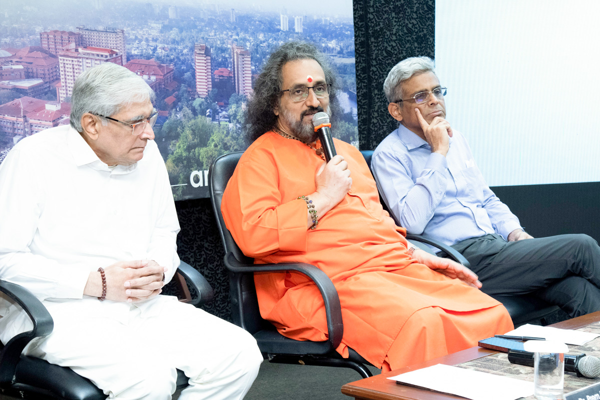 Swami Amritaswarupananda Puri seated with a microphone, answers questions from the press.