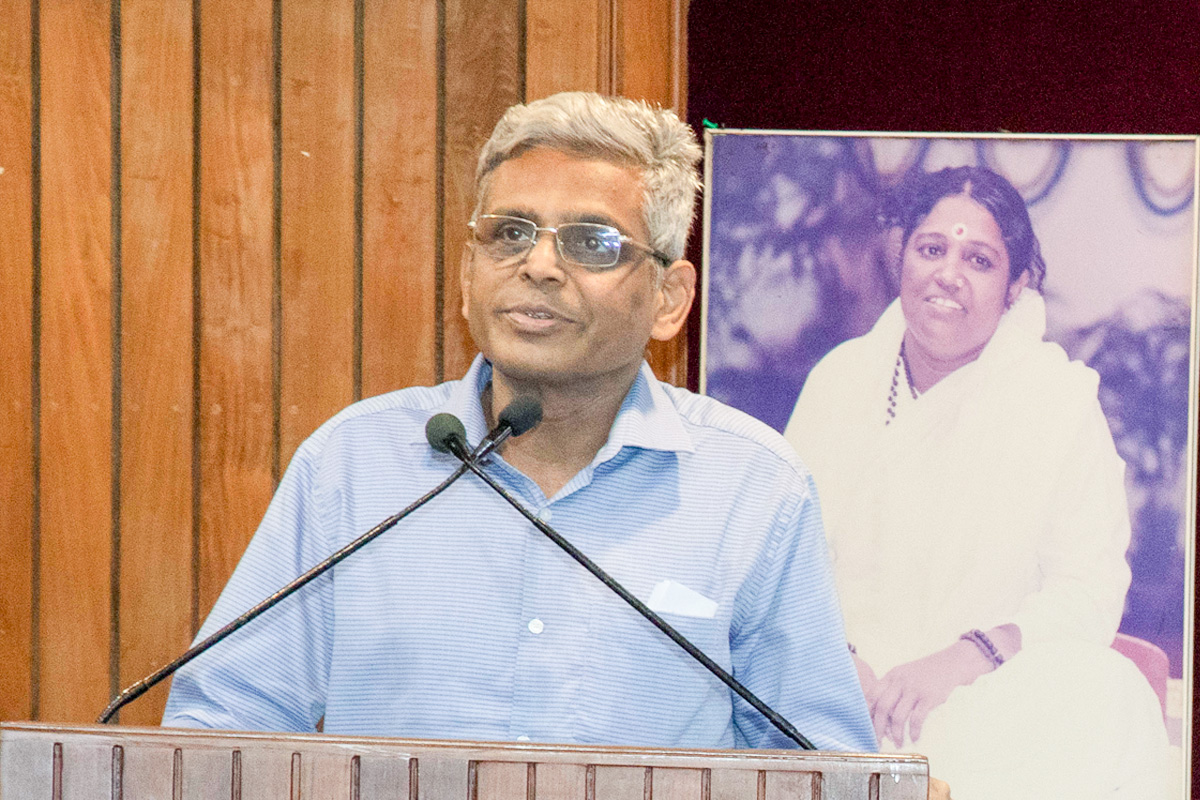 Dr Krishnakumar R, a doctor at Amrita Hospital for 25 years, standing at the podium in a light blue shirt and look of absolute wonder at the pinnacle achievements. .